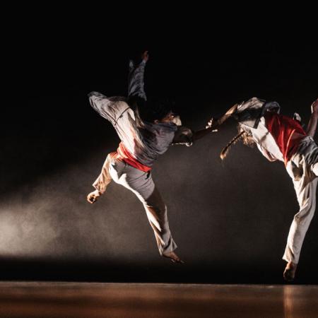 twee dansers in sprong in theaterzaal, kostuum gevechtskunst